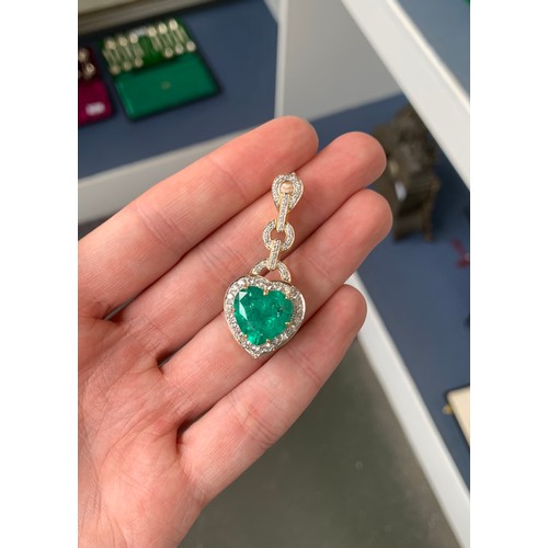 43 - An 18ct gold emerald and diamond pendant, the large heart cut Colombian emerald weighing 10.8cts and... 