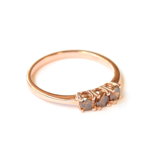 34 - A sterling silver ring with rose gold vermeil set with three orange/red diamonds, totalling 0.5cts, ... 