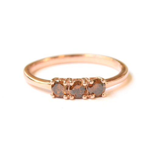 34 - A sterling silver ring with rose gold vermeil set with three orange/red diamonds, totalling 0.5cts, ... 