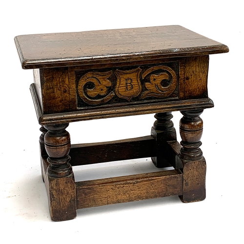 669 - A small oak lidded stool, the front carved with the monogram 'B' within a shield, 37x25x31cmH