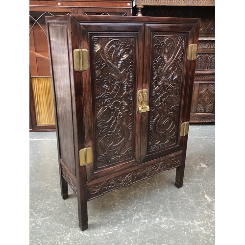 702 - A Chinese hardwood cabinet, the doors carved in low relief with dragons, 92x42x134cmH