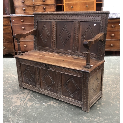 732 - An 18th century and later carved oak settle with hinged seat, 133cmW