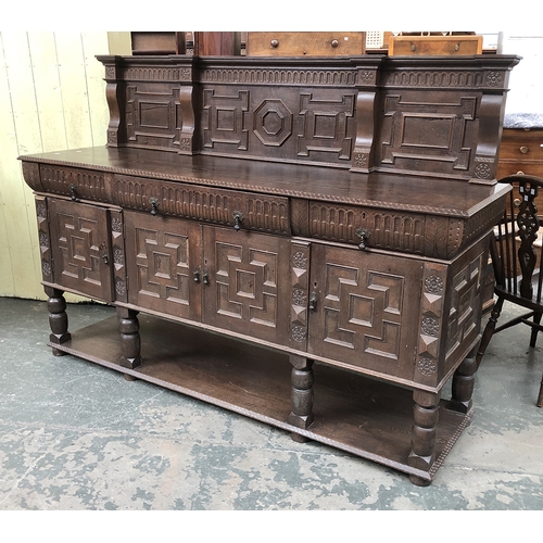 741 - A heavy carved oak sideboard, having three cushion drawers over four cupboard doors, each with geome... 