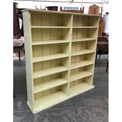 762 - A pale yellow painted bookcase, with two sections, each with six shelves, 155x32x169cmH