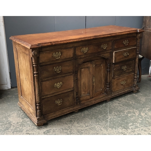 795 - A Victorian pine sideboard, central double cupboard doors surrounded by nine drawers, flanked by tur... 