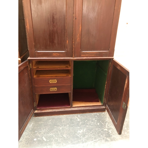 813 - A 19th century stained pine cupboard, panelled doors, the top with two slides, the base subdivided w... 