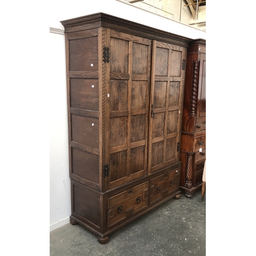 820 - A carved and panelled oak and pollard oak wardrobe, the doors opening to a hanging rail and hooks, o... 