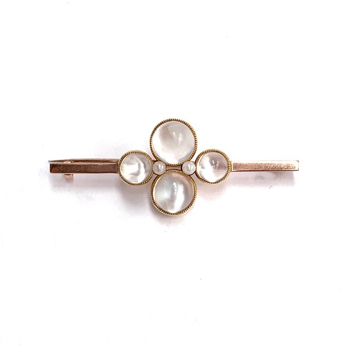 73 - An Edwardian 9ct gold bar brooch set with four bezel set moonstone bullet cabochons interspersed wit... 