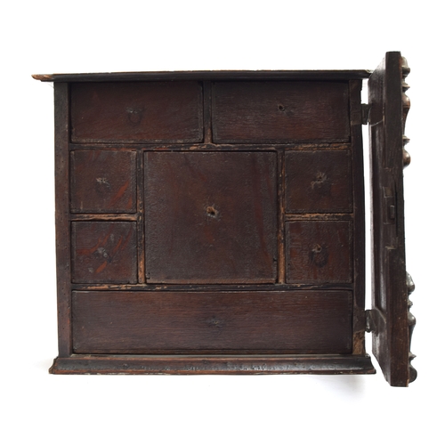 354 - A Charles II oak spice cupboard, the geometric carved door with applied half turned decoration, open... 