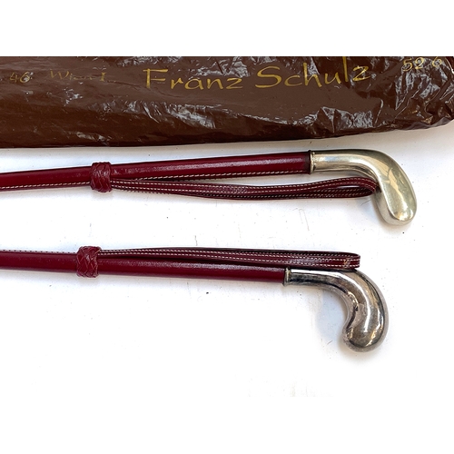 19 - A pair of red leather riding whips with 835 silver knops, each 80cm long and retailed by Franz Schul... 