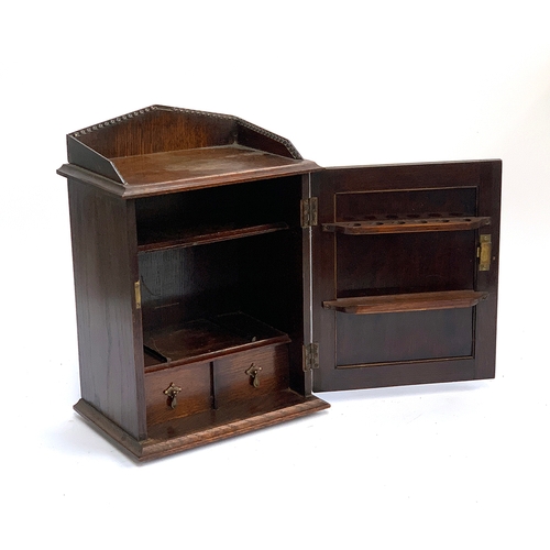 1216 - An oak smokers cabinet, opening to shelves, pipe rack and two drawers, 29cmW