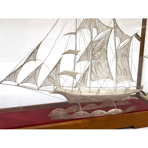 477 - A white metal filigree galleon in glazed display case, the case 22cmH; together with a similar white... 