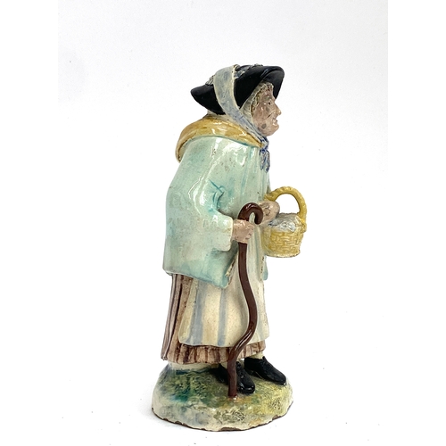 371 - A 19th century Staffordshire figure 'Age', an old woman holding a basket and stick, 17cmH