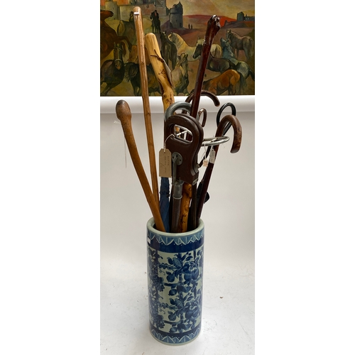 563 - A blue and white stick stand containing a quantity of sticks and umbrellas