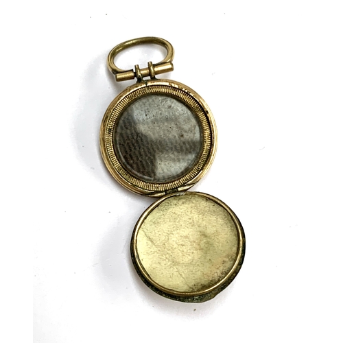 24 - A 19th century gilt metal locket with engine turned decoration, opening to reveal a glazed panel of ... 