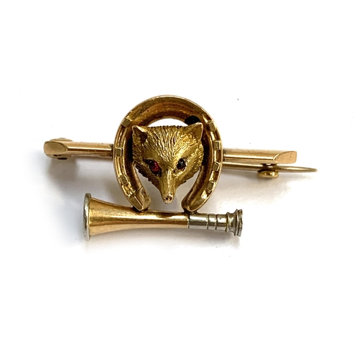 111A - A late Victorian gold brooch in the form of a fox mask, horseshoe and hunting horn, set with red cab... 