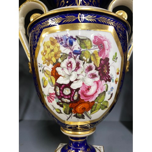 191 - A matched pair of Derby style twin handled urns, cobalt blue and heightened in gilt with large hand ... 