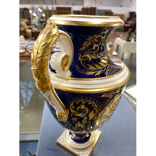 191 - A matched pair of Derby style twin handled urns, cobalt blue and heightened in gilt with large hand ... 