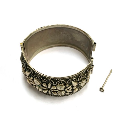 19 - An Indian white metal bangle with hinged mechanism securing with pin, 6.2cmW