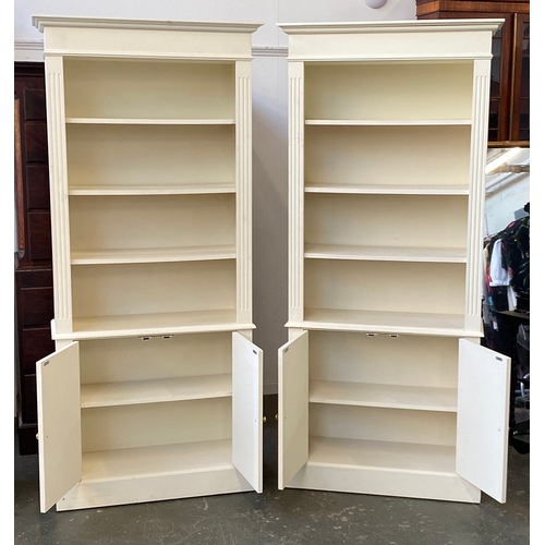 1147 - A pair of modern white painted bookcases, each with four shelves over panelled cupboards, 90x36x199c... 