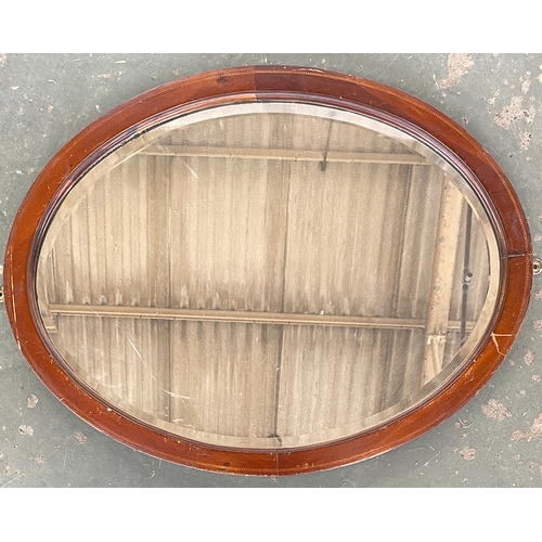 778 - An Edwardian mahogany oval mirror, with barbers pole stringing and bevelled plate, 65x50cm