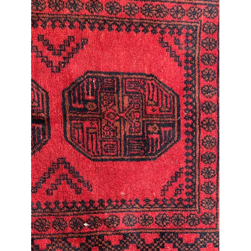 793 - A red ground tekke style rug with two central medallions, 106x144cm