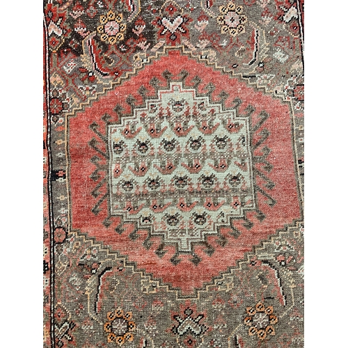 794 - A red ground rug with central medallion within a hexagon, considerable fading, 125x170cm