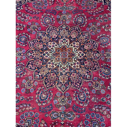 798 - A red ground rug with floral borders, foliate centre sprays, and a central lotus, 350x410cm