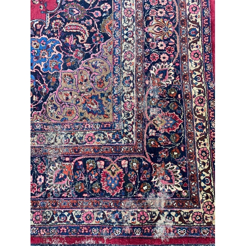 798 - A red ground rug with floral borders, foliate centre sprays, and a central lotus, 350x410cm