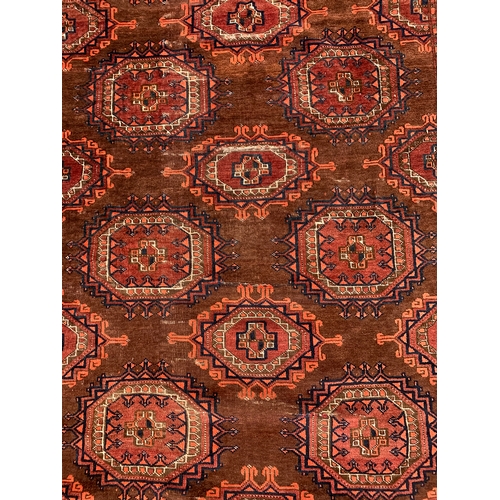 800 - An orange/brown tekke style rug with 9 whole medallions, 143x215cm