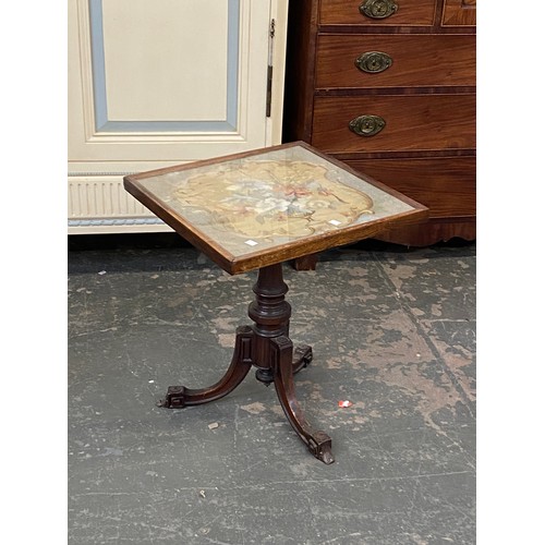 1024 - A tripod table with glazed top above a floral wool work, 49x50x57cmH