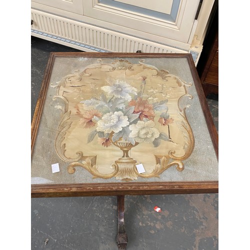 1024 - A tripod table with glazed top above a floral wool work, 49x50x57cmH