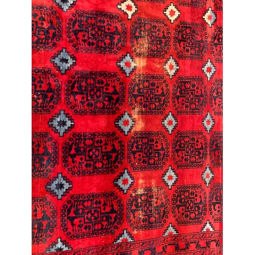 629 - A red ground rug with 105 medallions, 287x452cm