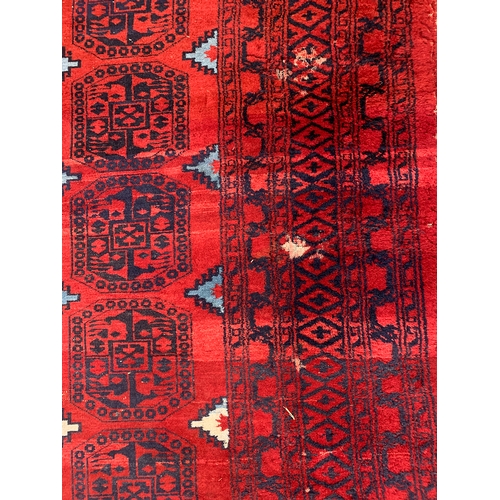 629 - A red ground rug with 105 medallions, 287x452cm