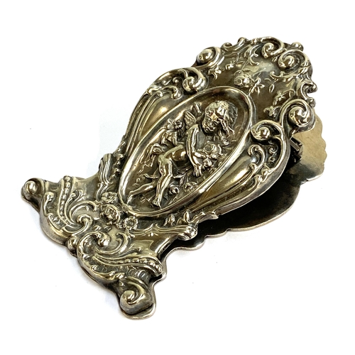 61 - An Edwardian silver desk paper clip chased with putti, hallmarked for Birmingham 1903, 7.5cmL, 43.7g