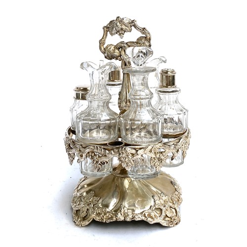 87 - A silver plated cruet set, holding six cut glass bottles/jars, chased with grape and vine detail, 27... 