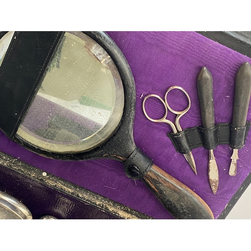 348 - An early 20th century leather vanity set, the glass dressing table bottles with silver plated lids, ... 