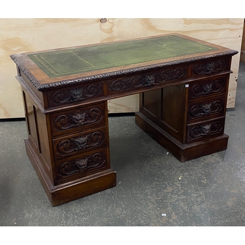 906 - A carved oak pedestal desk with a traditional arrangement on nine drawers