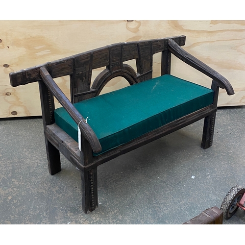 914 - An Eastern hardwood and iron bench with green upholstered cushion, 146cmW