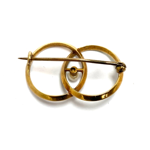 119 - An Edwardian gold and enamel brooch designed as interlocking circles set with a central pearl, ermin... 
