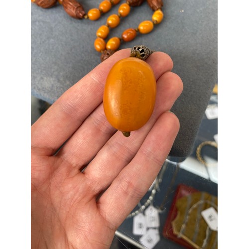 51 - An early 20th century amber bead necklace, the knotted beads each approx. 13mm long, interspersed wi... 