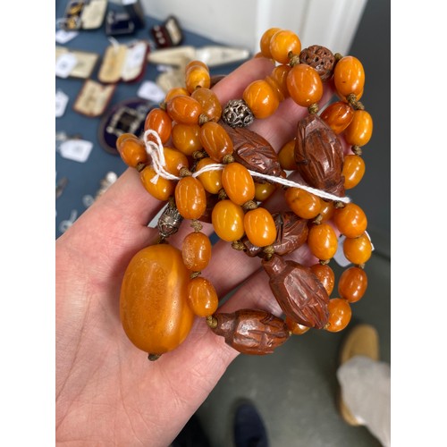 51 - An early 20th century amber bead necklace, the knotted beads each approx. 13mm long, interspersed wi... 