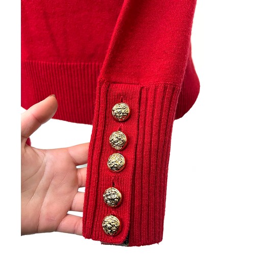 1949 - A Burberry red cashmere knitted women's jumper with gold buttons detailing on shoulder and cuffs, ri... 