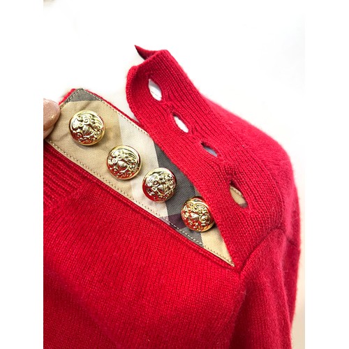 1949 - A Burberry red cashmere knitted women's jumper with gold buttons detailing on shoulder and cuffs, ri... 