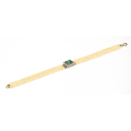 33 - An Edwardian three strand seed pearl bracelet with central rectangular bluish-green tourmaline surro... 