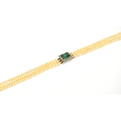 33 - An Edwardian three strand seed pearl bracelet with central rectangular bluish-green tourmaline surro... 