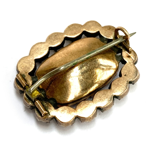 21 - A Georgian gold brooch set with central amethyst paste surrounded by black dot paste, 3cmW