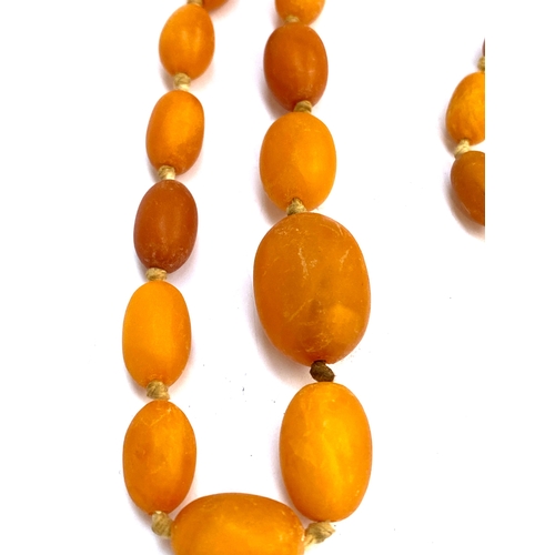 26 - An early 20th century amber bead necklace (no clasp), the beads graduating from 11mm to 21mm long, g... 