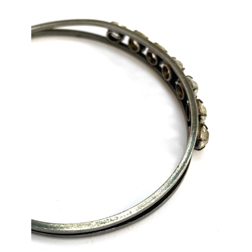 40 - An early 20th century white metal and claw set paste bangle, 7.3cmW, 17g