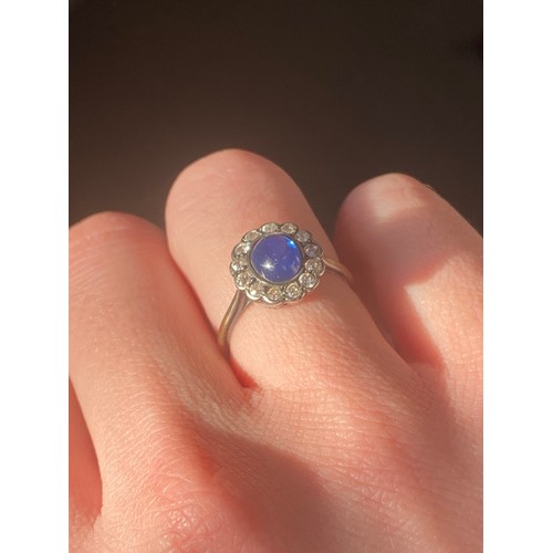 24 - An early 20th century 18ct gold, sapphire cabochon and diamond cluster ring, the sapphire measuring ... 